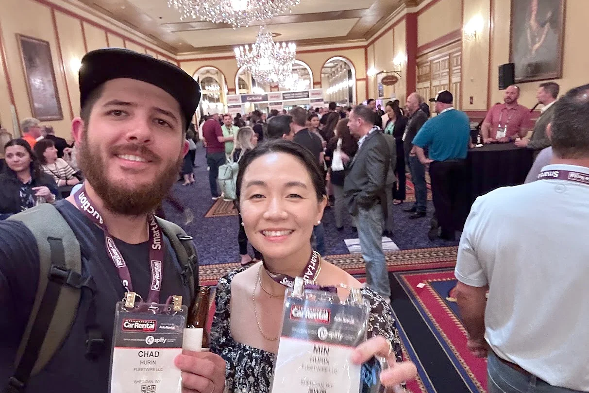 Chad and Min holding up their exhibitor badges in the busy expo hall