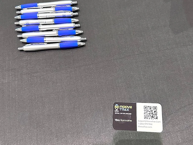 MooveTrax business card on the Fleetwire booth table next to a row of Fleetwire pens